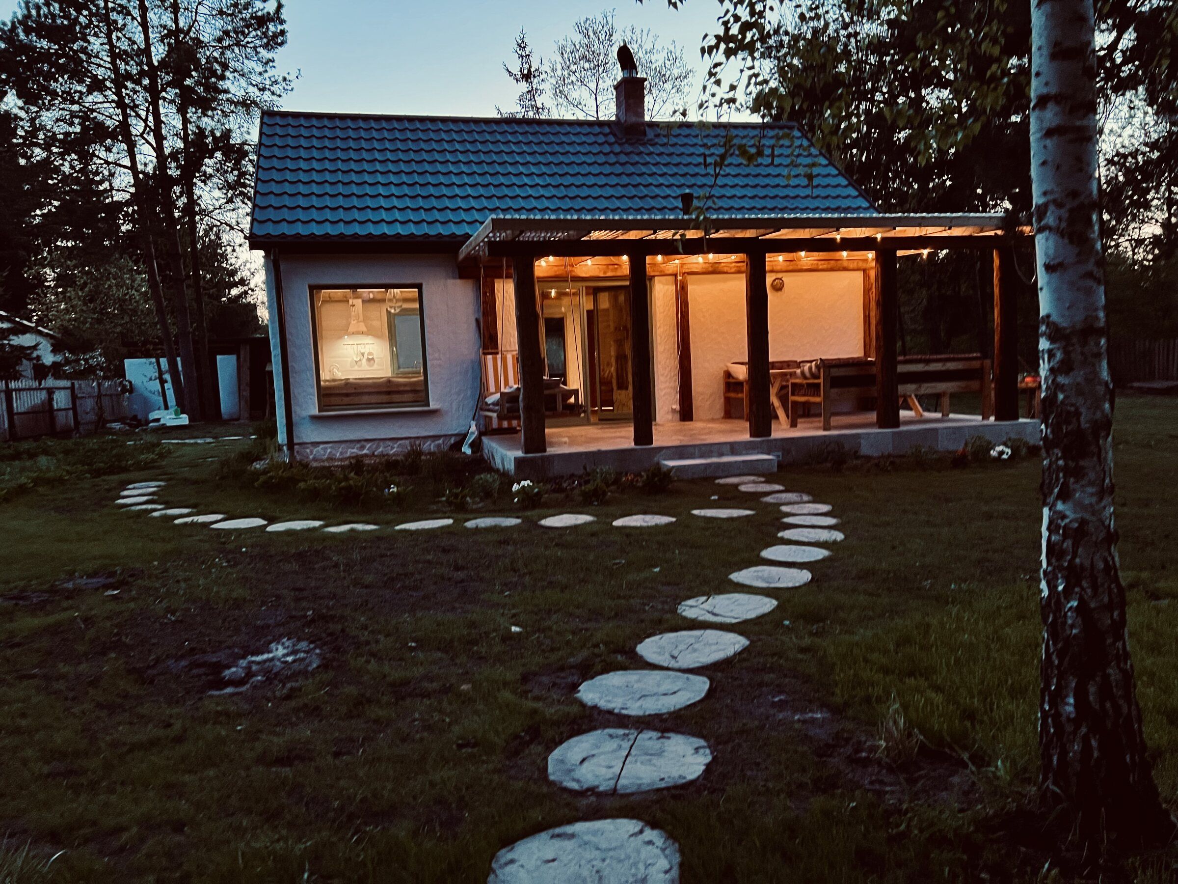 Domek Polny wieczorem, oświetlony taras i kamienna ścieżka